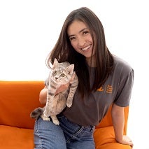 Woman sitting on orange chair and holding a kitten