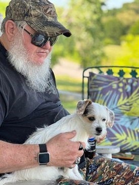 Man with beard wearing sunglasses holding puppy