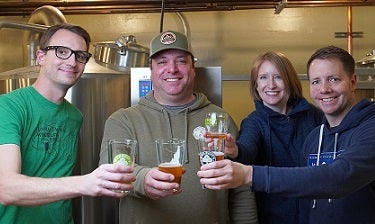 Four people with glasses of beer at brewery