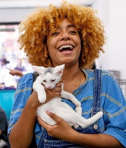 Woman in blue shirt holding white kitten