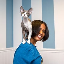 Woman in blue shirt with white and gray cat standing on her shoulder