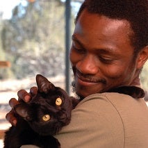 Man in tan shirt holding black cat