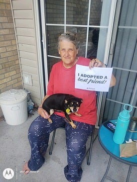 Woman with puppy holding adoption sign