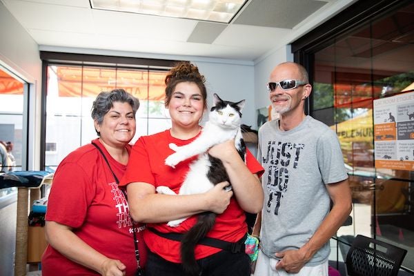 a family posing with their newly adopted black and white cat