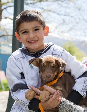 Young boy in black and white shirt holding brown puppy