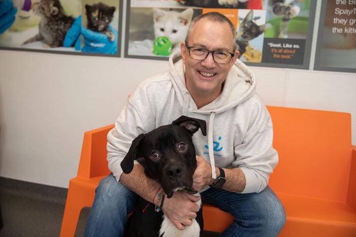 A man with a black dog in an animal shelter