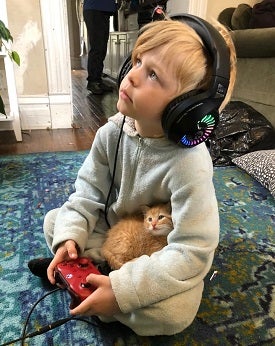 Boy wearing headphones with kitten in lap