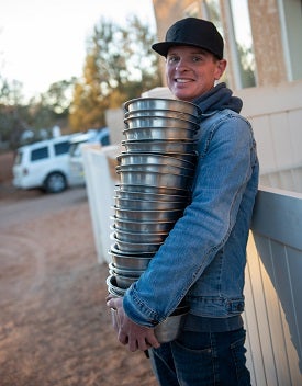 Man carrying stack of dog bowls