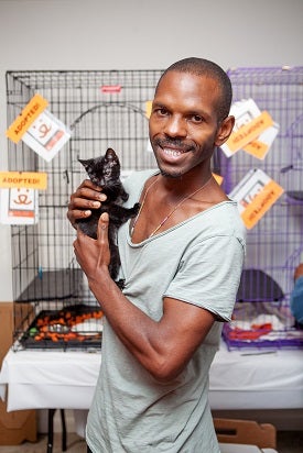 Man in gray shirt holding black kitten
