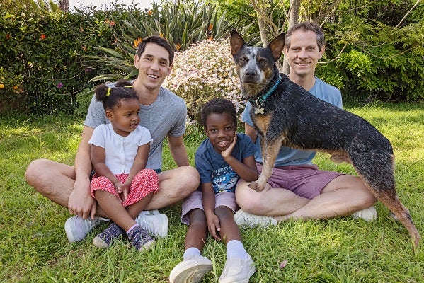 Couple with two kids with dog standing on man's leg