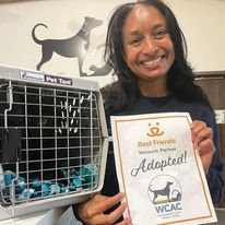 Woman holding adopted sign next to cat carrier