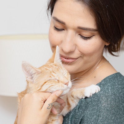 a woman holding an orange cat