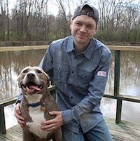 Nick Walton posing with his dog on a dock next to a lake