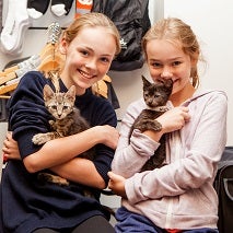 Two young girls holding kittens