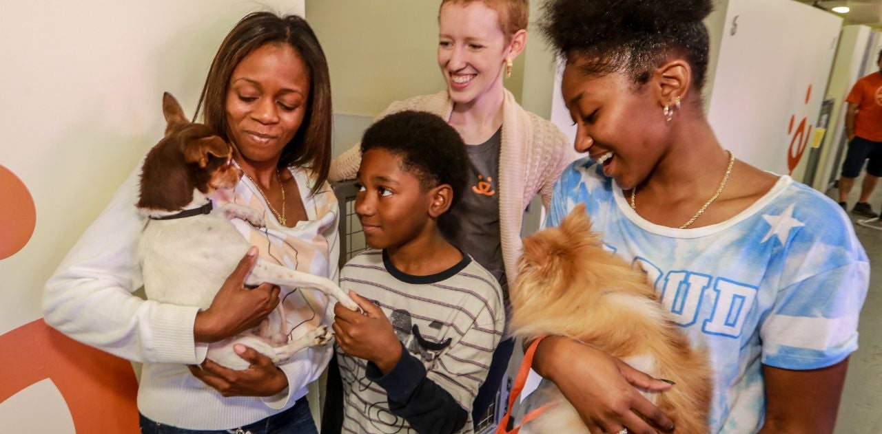 A family of three and an adoption counselor hold two dogs at the Best Friends Lifesaving Center in Atlanta