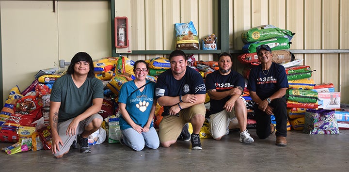 Group of people sitting in front of a large pile of donated items