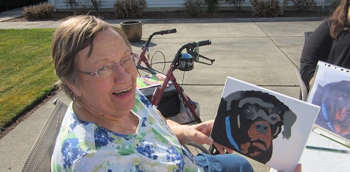 Woman showing off painting of black and brown dog