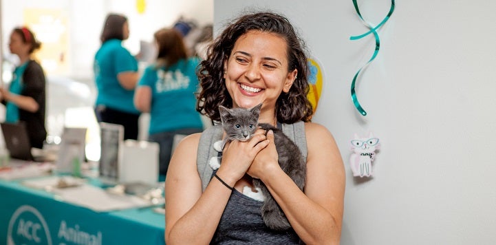 Woman holding a kitten in front of adoption table