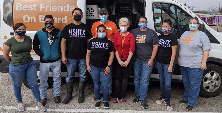 Nine people with masks standing in front of the side of open Best Friends transport van 